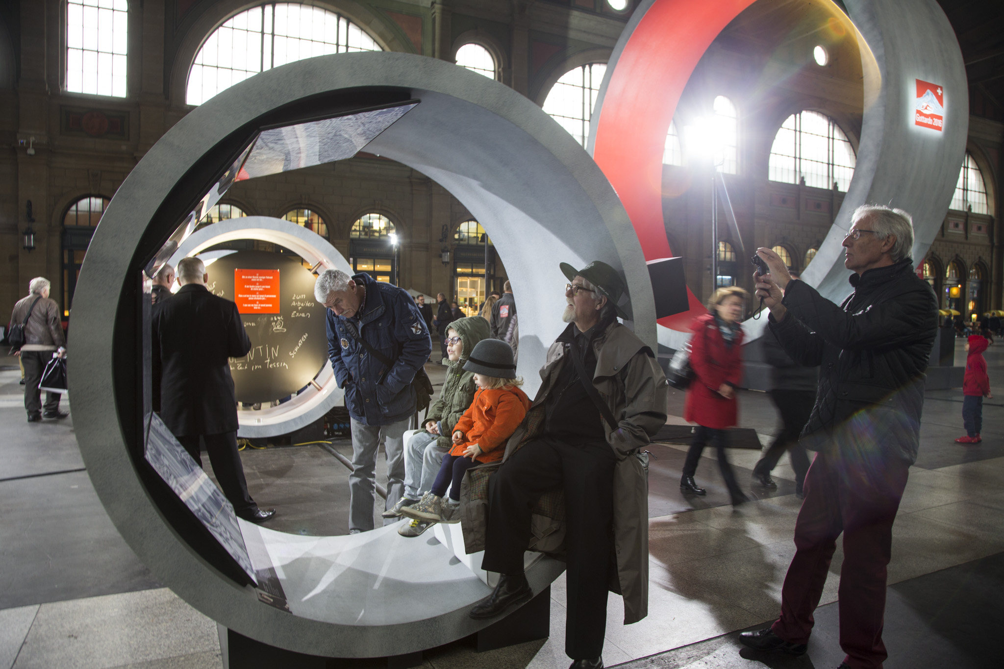Visitors of all ages sitting inside one of the concrete tunnel modules at the Gottardo 2016 exhibition