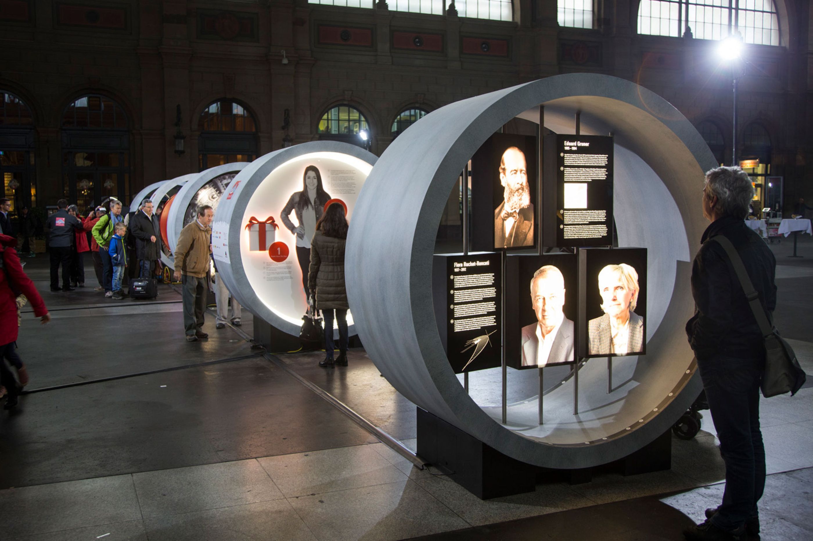 The row of Gottardo 2016 tunnel modules with portrait and text panels, visitors reading along the installation