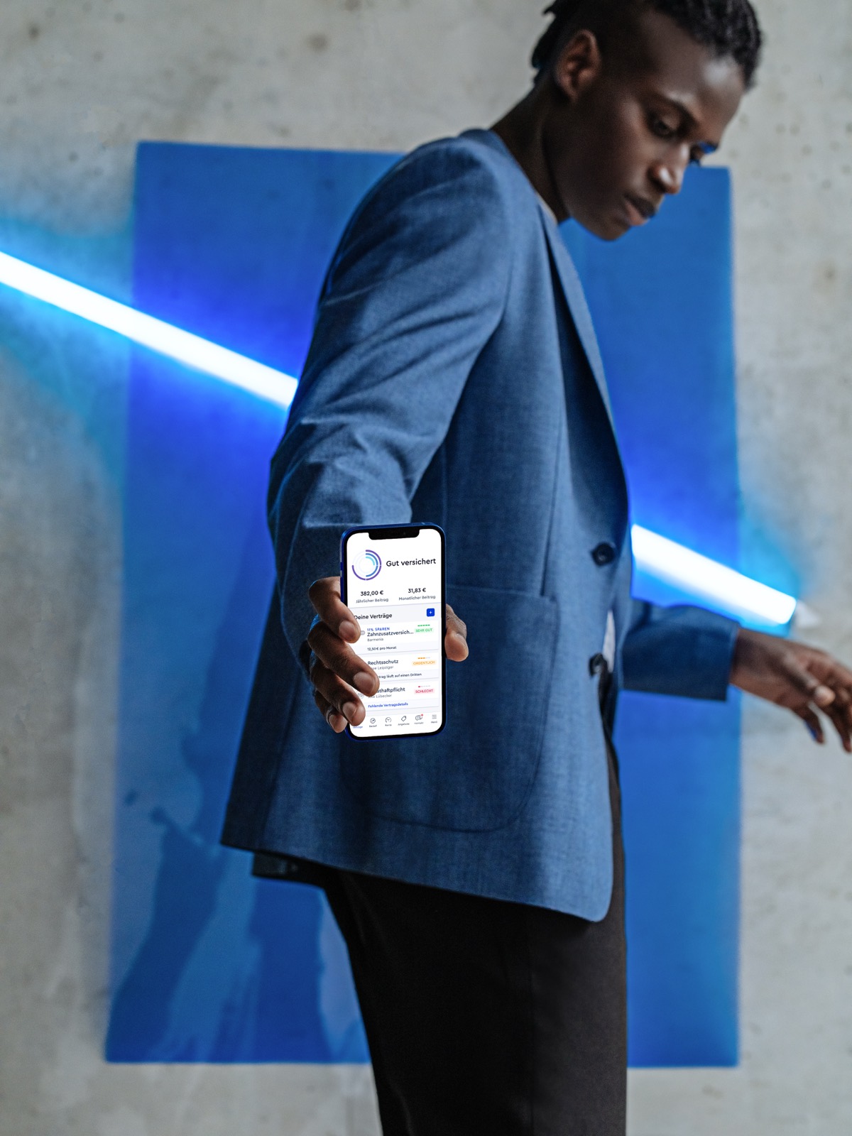 CLARK product photography — model in a blue blazer presenting the phone, blue neon light bar, concrete backdrop