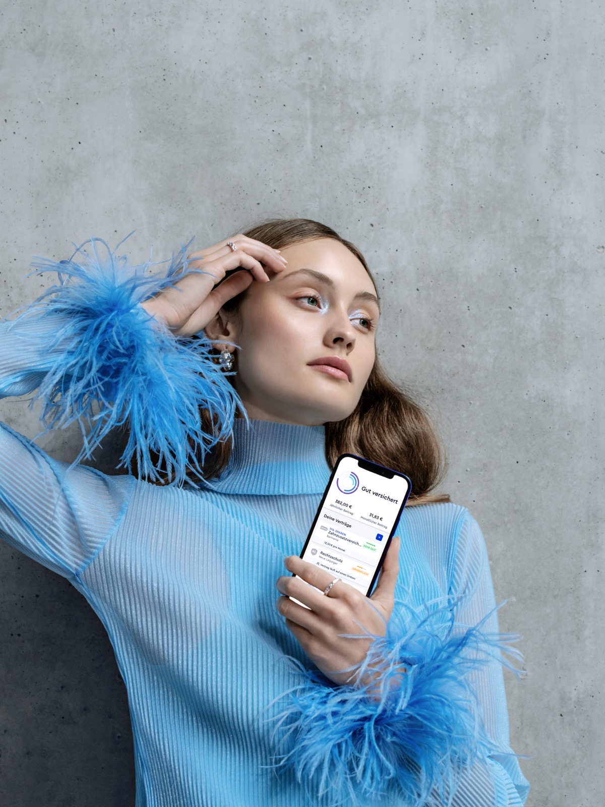 CLARK product photography — model in a blue feathered top leaning against concrete, holding the CLARK app, editorial gaze